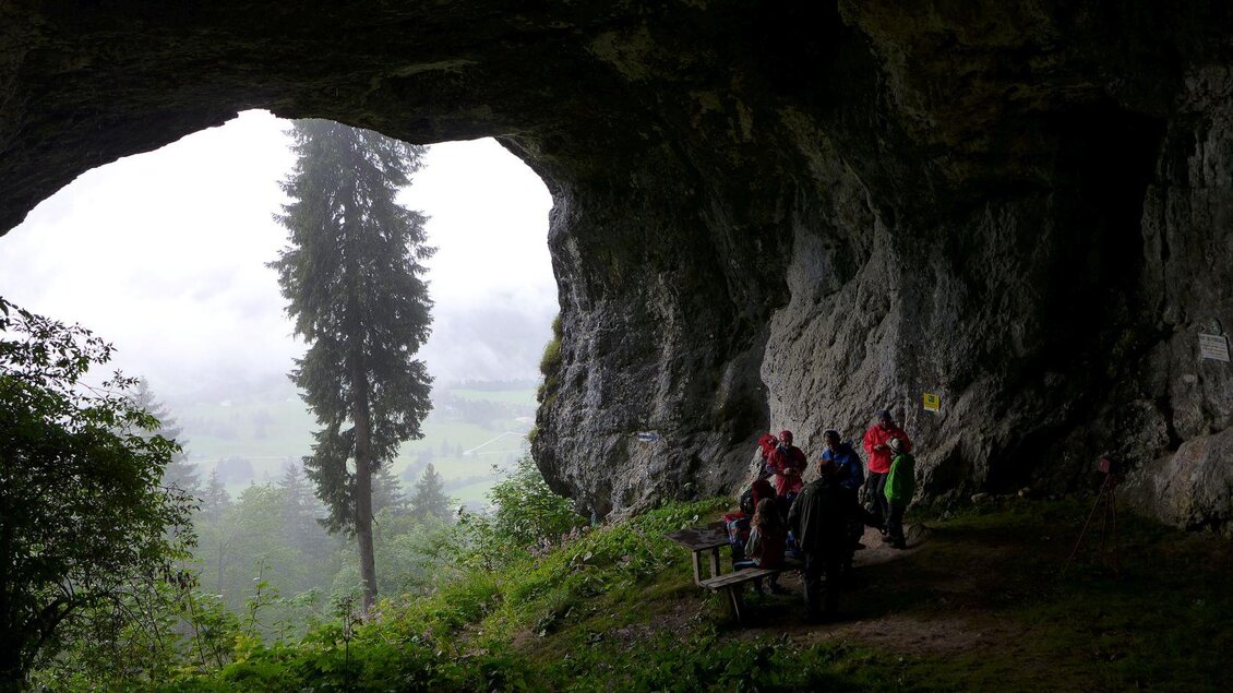 <p><p>Eine Höhle, das Lieglloch, mit Blick auf eine neblige Landschaft. Einige Wanderer sitzen auf einer Bank und genießen die Aussicht.</p></p> | © Robert Seebacher