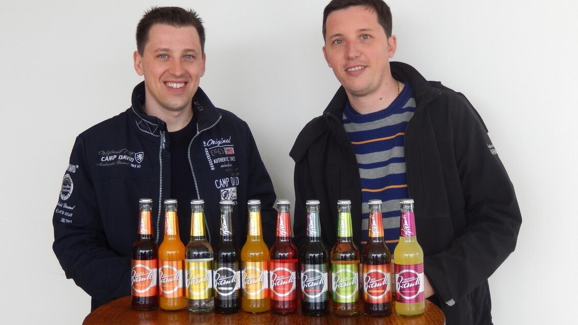 Zwei Inhaber präsentieren Brantl Limonaden in verschiedenen Sorten an einem Tisch in Köflach. | © Creativ Media Kos