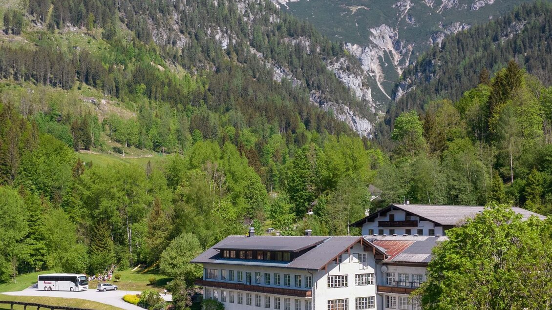 Ein malerisches Gebäude umgeben von grünen Wäldern und Bergen. Der klare Himmel ergänzt die idyllische Landschaft. | © Lodenwalker Ramsau