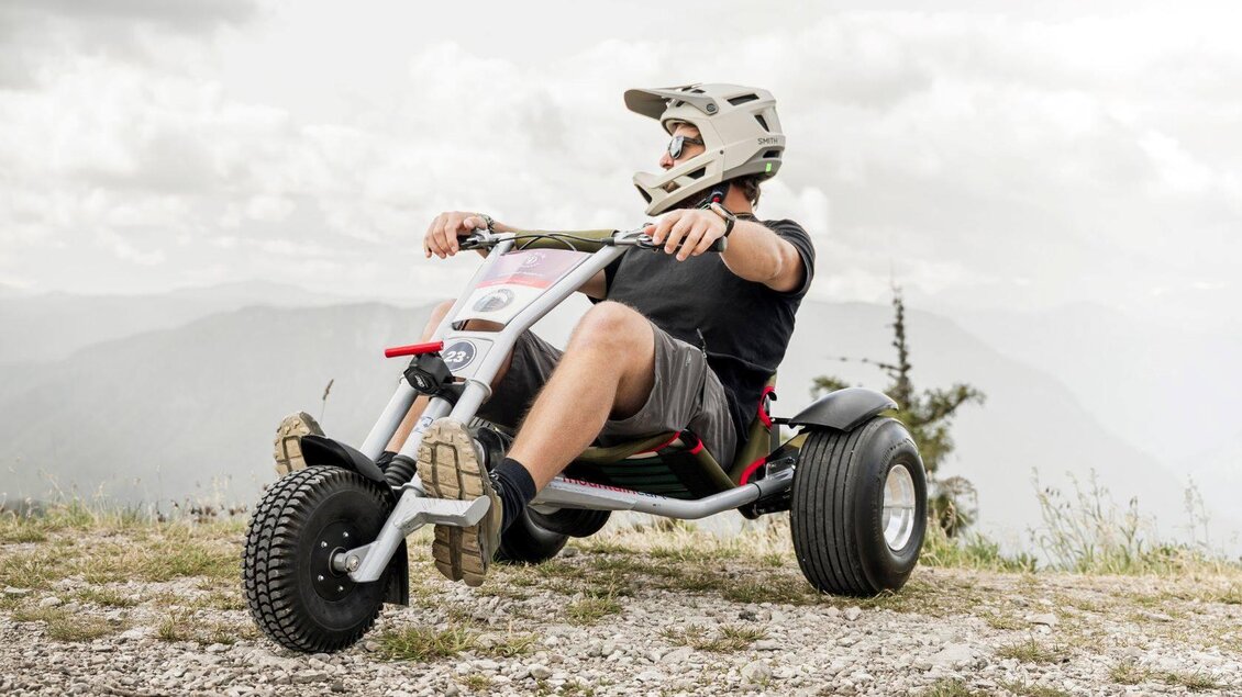 Ein Fahrer sitzt in einem der Mountaincarts der Loser Legends am Loser in Altaussee. Im Hintergrund sind die Berge des Ausseerland Salzkammergutes zu sehen.  | © Loser Legends - Mountaincart Salzkammergut