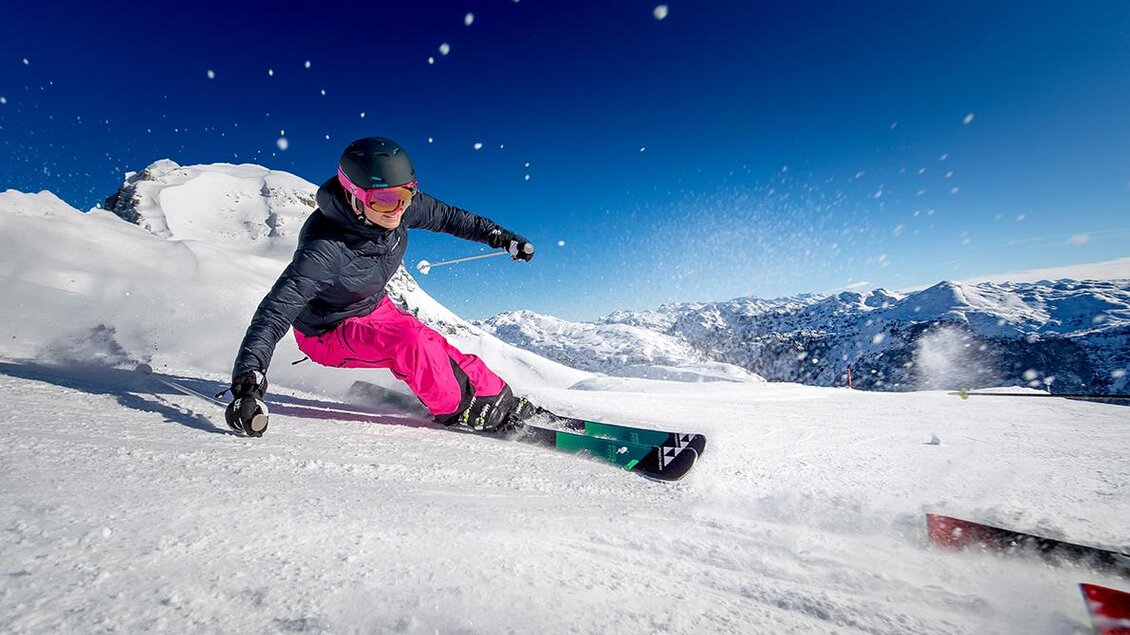 <p>Eine Skifahrerin fährt auf dem frischen Schnee die Piste am Loser hinunter. Im Hintergrund ist die Berglandschaft des Ausseerlandes und ein blauer Himmel zu sehen.</p> | © TVB Ausseerland - Salzkammergut / Tom Lamm