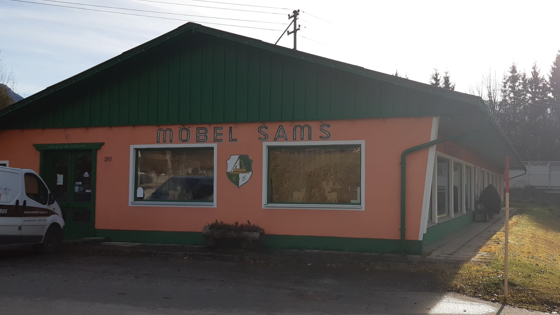 Ein Möbelgeschäft mit dem Namen "Möbel Sams". Das Gebäude ist orange mit einem grünen Satteldach und großen Fenstern. | © TVB Ausseerland Salzkammergut_Daniela Casari