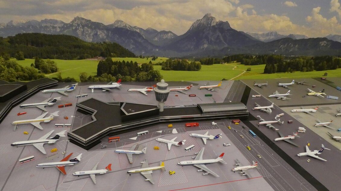 Ein Modell eines Flughafens mit zahlreichen Flugzeugen und einem Kontrollturm. Im Hintergrund sind die Berge und eine grüne Landschaft zu sehen. | © Helmut Kaiser
