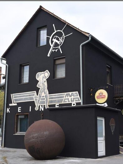 Black building of the MadClub Kosir with wall graphics and guests in front of the entrance in Bärnbach. | © keine Kenntnis