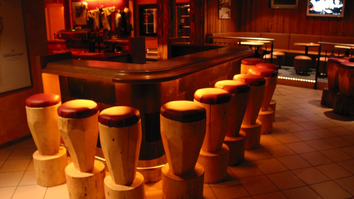 Marios Pizzeria Sportalm Tauplitz. Eine gemütliche Bar mit hölzernen Sitzplätzen und sanfter Beleuchtung. Im Hintergrund sind Tische und eine Fernseher zu sehen. | © Mario Seebacher