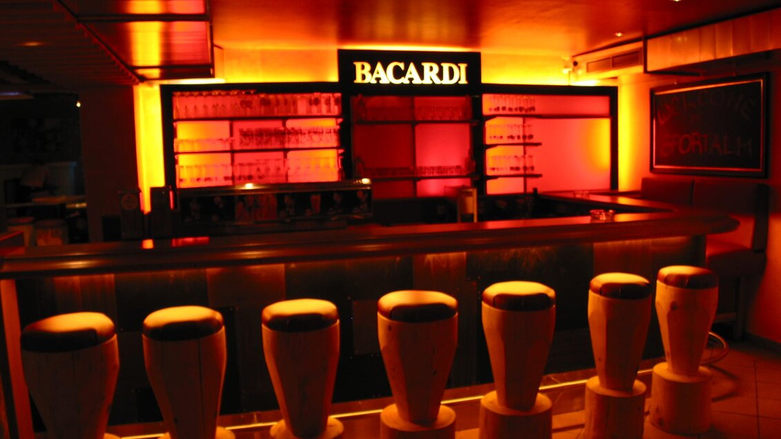 Marios Pizzeria Sportalm Tauplitz Eine stilvolle Bar mit bunten Lichtern und einem Bacardi-Schild. Hohe Barhocker stehen vor der Theke. | © Mario Seebacher