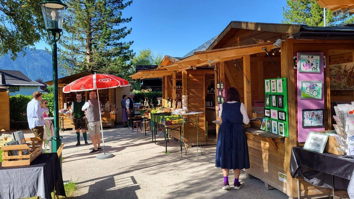 <p>Ein lebhafter Markt im Kurpark Altaussee mit Holzständen und einer Vielzahl von Kunsthandwerk. Leute bummeln umher und genießen das schöne Wetter.</p> | © Petra Kirchschlager