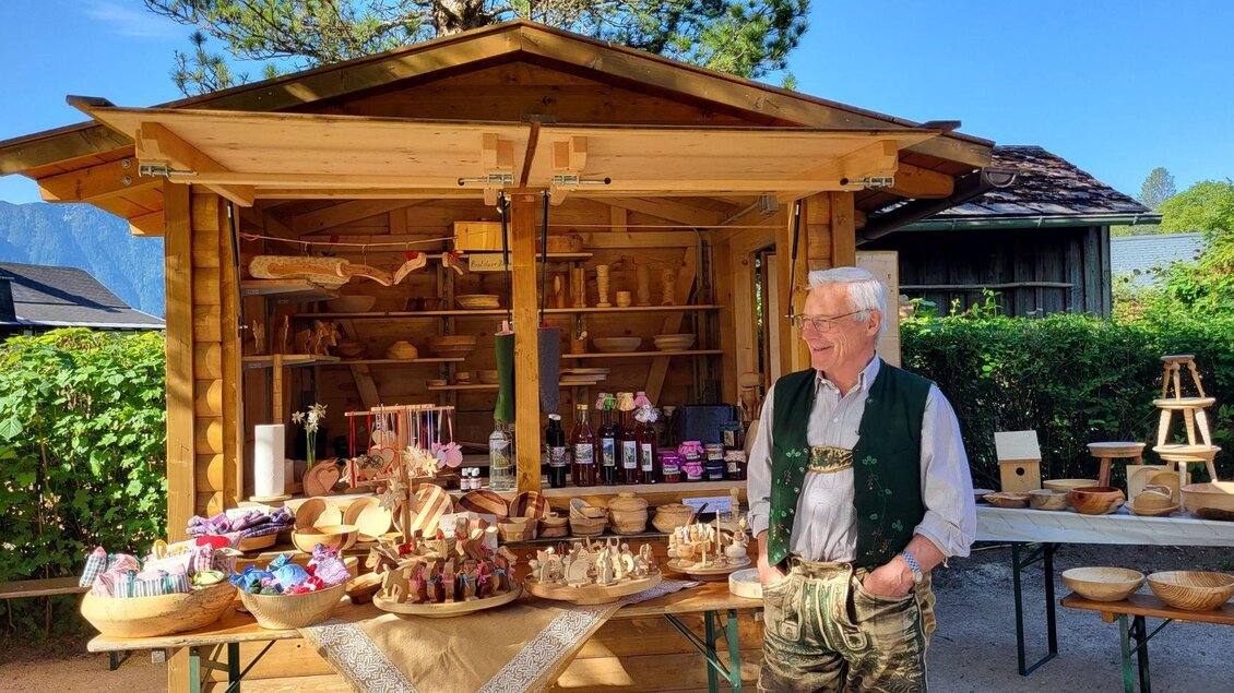 Der Markstand der Familie Egger aus Lupitsch. Handgefertigte Holzartikeln, Schnaps und weitere selbgemachte Erzeugnisse werden angeboten. Franz trägt eine Lederhose und ist gut gelaunt.  | © Petra Kirchschlager