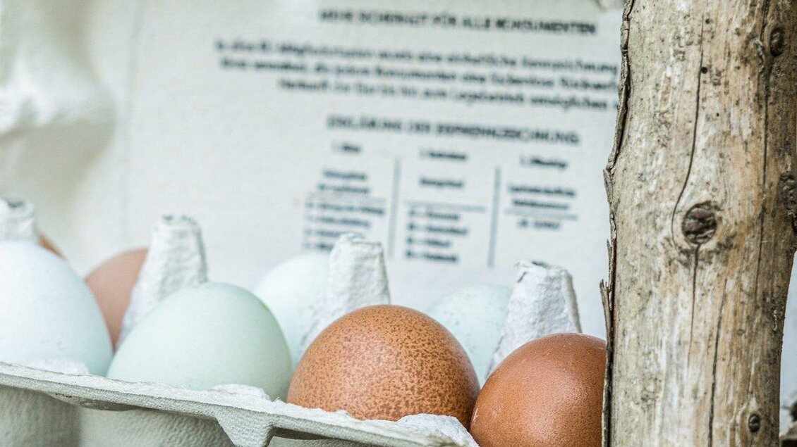 Ein Eierkarton mit verschiedenen Eiern in verschiedenen Farben. Neben dem Karton ist ein Stück Holz sichtbar. | ©  Martin´s das schmeckt