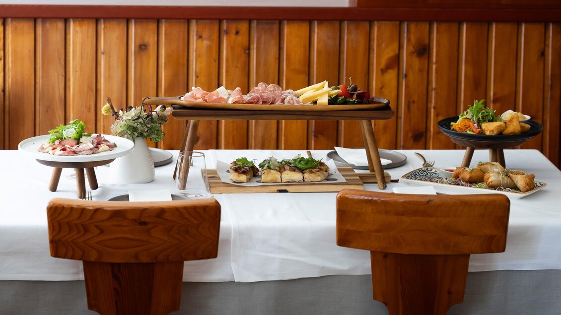 Ein schön gedeckter Tisch mit verschiedenen Platten voller köstlicher Speisen. Es gibt Fleisch, Käse, Gemüse und Snacks, umgeben von Holzwänden. | © Stadthotel zur goldenen Krone