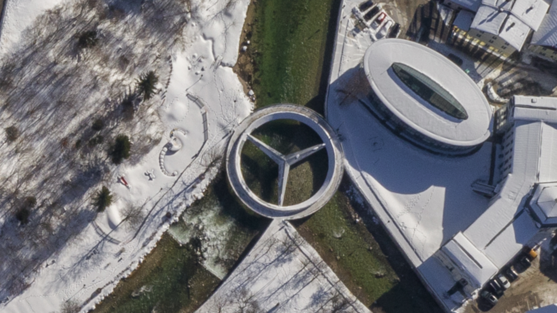 Die schneebedeckte Landschaft von Bad Aussee mit der modernen, kreisförmigen Mercedessternbrücke am Zusammenfluss der Grundlseer und Altausseer Traun. Im Hintergrund ist ein architektonisches Gebäude sichtbar, in welchem sich auch das Tourismusbüro Bad Aussee befindet.
 | © Karl Grieshofer