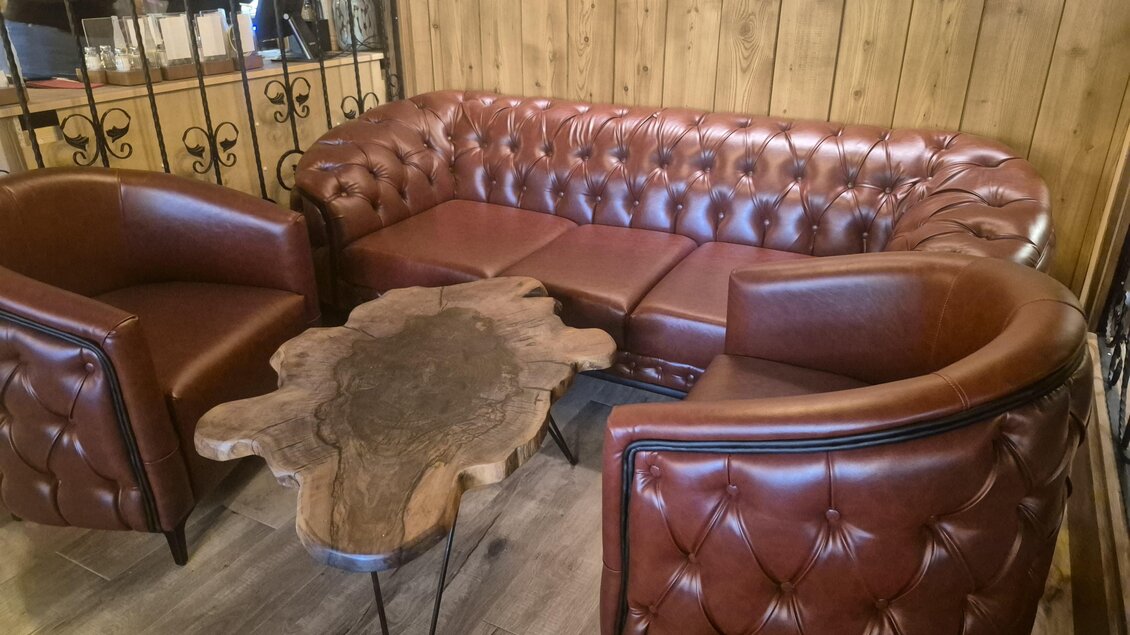 Ein gemütliches Ledersofa im Chesterfield-Stil mit passenden Sesseln. Dazu ein rustikaler Couchtisch aus Holz. | © TV Hochsteiermark_A.Stelzer
