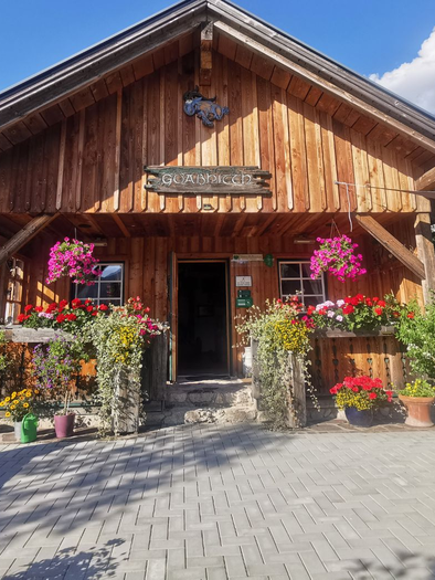 <p>Der Eingang in die Hütte mit bunten Blumen und Pflanzen im Vordergrund. Der Himmel ist blau mit einigen Wolken.</p> | © TVB Ausseerland Salzkammergut_Theresa Schwaiger
