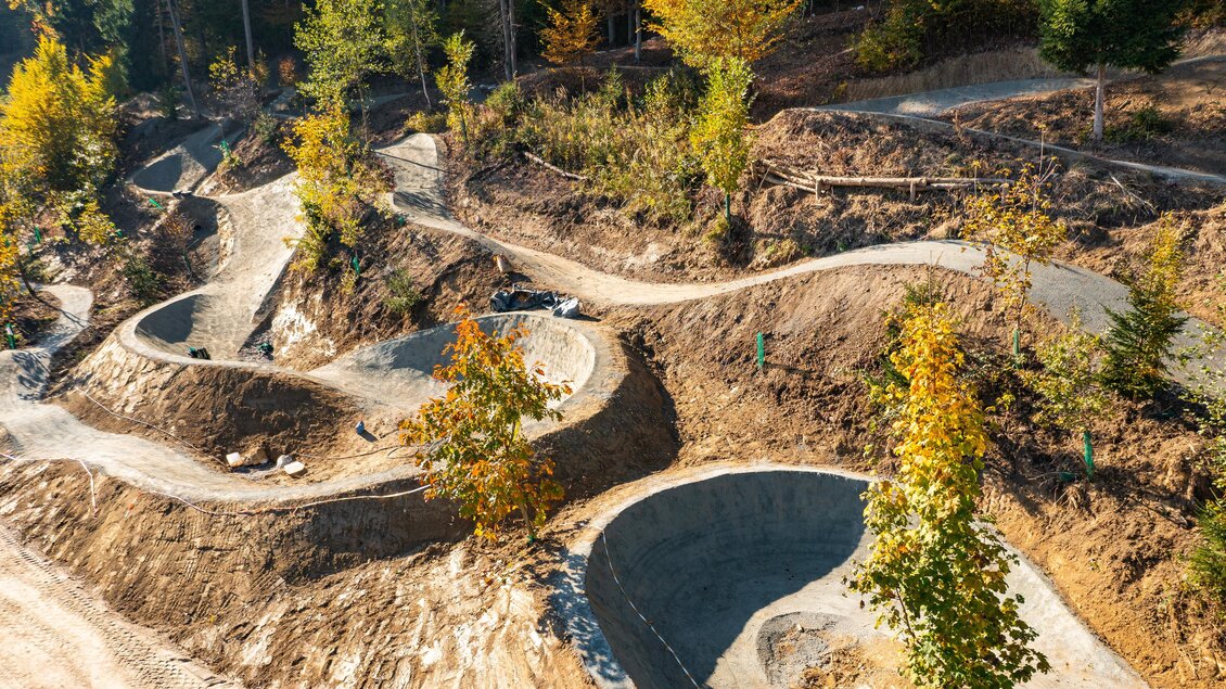 Eine kurvenreiche Mountainbike-Strecke umgeben von Bäumen im Herbst. Die Landschaft zeigt kreative Gelände-Formen mit einer schönen Aussicht. | © MG Lannach - Petru Rimovetz