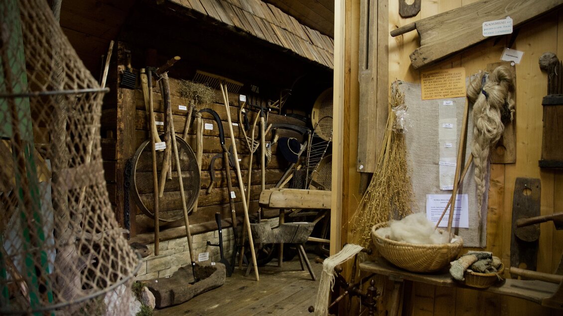 Ein traditioneller Raum mit verschiedenen Werkzeugen und landwirtschaftlichen Geräten. Die Wände sind aus Holz und die Atmosphäre ist rustikal und historisch. | © TV ERZBERG LEOBEN