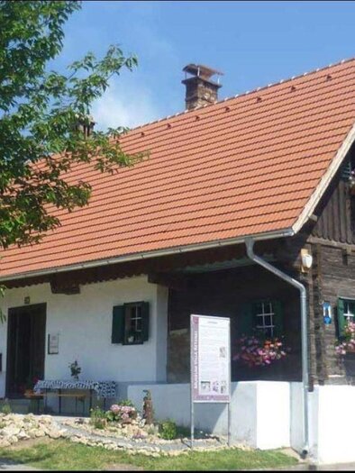 Ein traditionelles Schweizer Haus mit einem roten Satteldach und grünen Fensterläden. Blumen schmücken die Fenster, und die Umgebung ist grün und einladend. | © Museum Villa Retznei