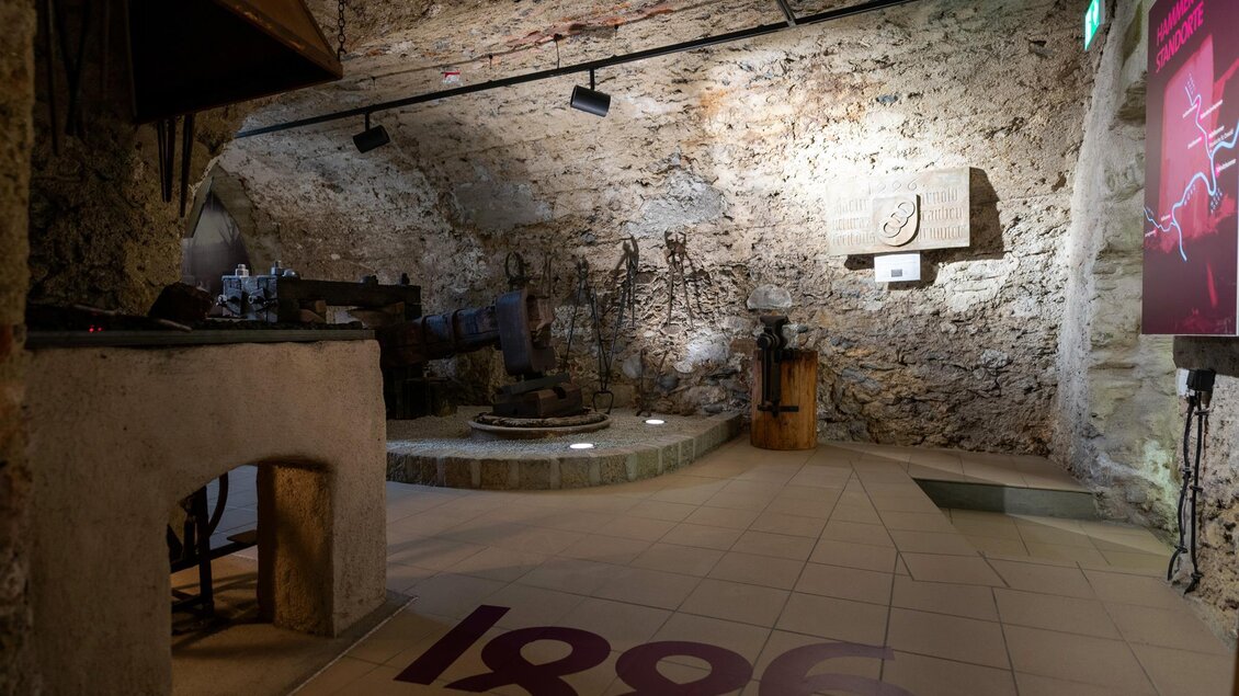 Ein historischer Raum mit Steinwänden und Werkzeugen. In der Mitte befindet sich eine runde Fläche, die den Blick auf die interessante Ausstellung lenkt. | © Stadtgemeinde Kapfenberg