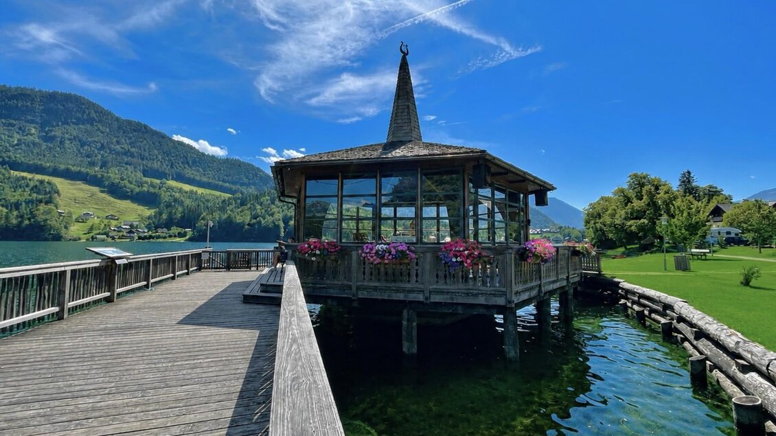 Ein hübsches Holzgebäude am Wasser mit einem spitzen Dach. Die Umgebung ist grün und die Berge bieten eine schöne Kulisse. | © Tourismusverband Ausseerland