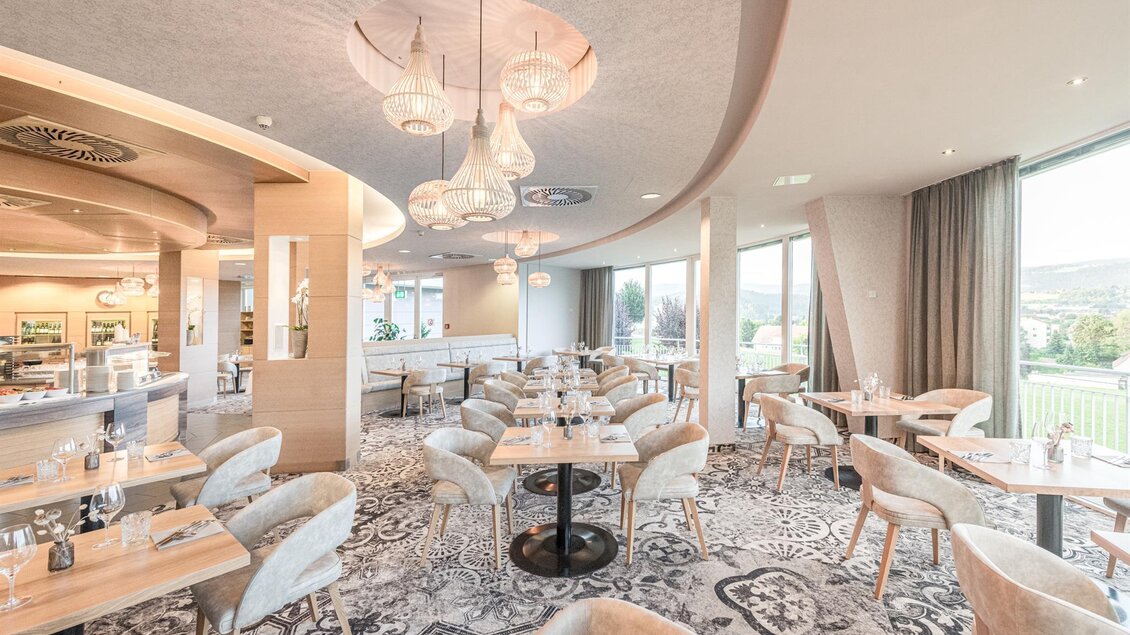 NOVA Panoramarestaurant in der Therme NOVA Köflach mit gedeckten Tischen, Sesseln, großen Fenstern und Blick in die Landschaft. | © Hotel & Therme NOVA