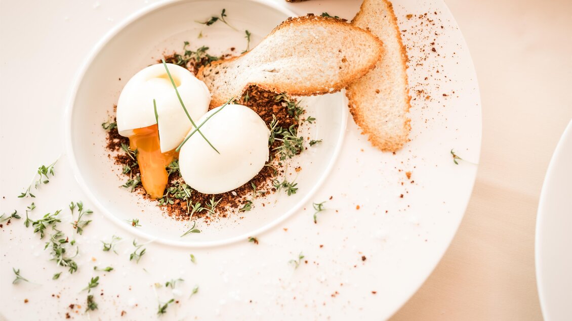 Weißer Teller mit fein angerichtetem Gericht, Gemüse, Ei und knusprigem Brot im Panoramarestaurant in der Therme NOVA in Köflach.  | © Die Abbilderei