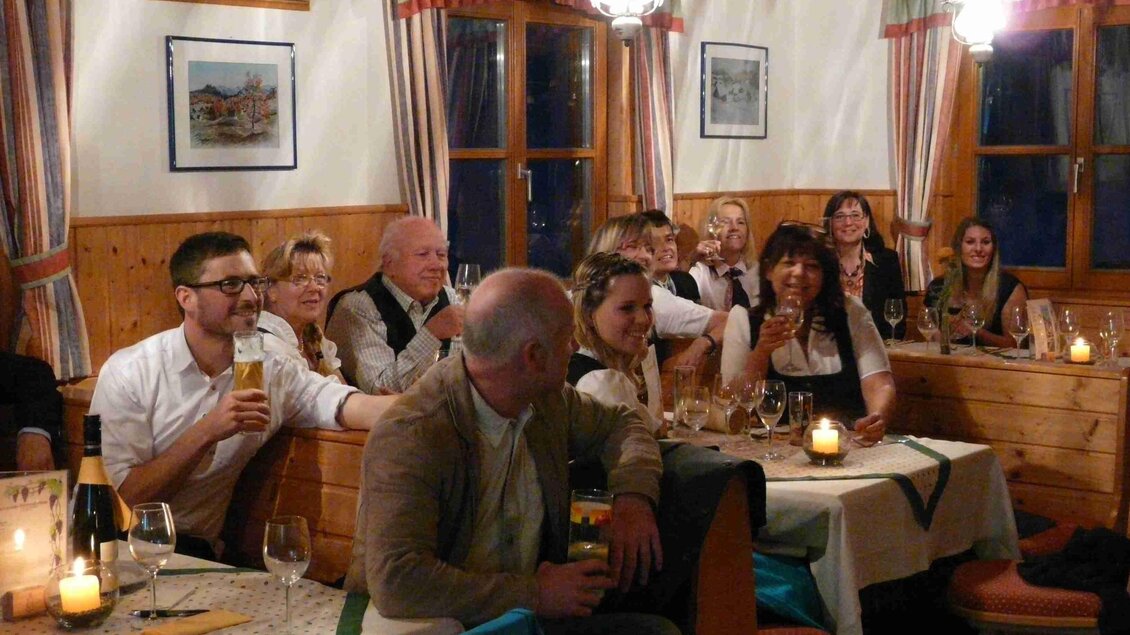 <p>In der gemütlichen Skihütte Grafenwiese sitzen mehrere Menschen an den Tischen und feiern gemeinsam. Die Beleuchtung ist warm und einladend.</p>