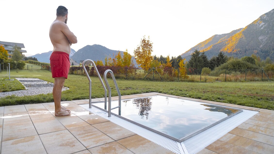 <p>Ein Mann steht am Rand eines kleinen Außenpools beim Narzissen Vital Resort in Bad Aussee und schaut auf die Berge. Die Landschaft des Ausseerlandes ist in herbstliche Farben getaucht.</p>  | © Thomas Lahnsteiner