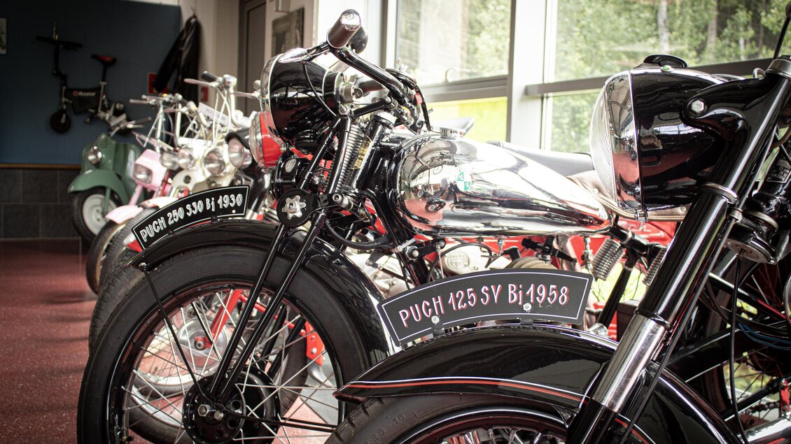 Eine Ansammlung von klassischen Motorrädern in einem Ausstellungsraum. Die Fahrzeuge sind glänzend und gut erhalten, mit verschiedenen Modellen und Farben. | © Natechnikum