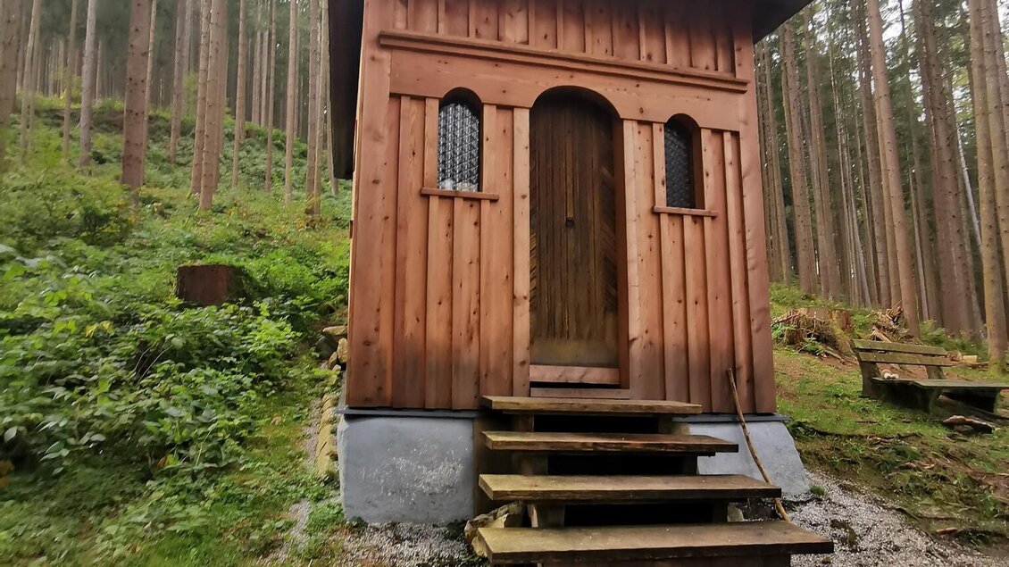 Ein kleines Holzhaus steht im Wald, umgeben von hohen Bäumen. Der Eingang hat Stufen und neben den Fenstern sind kleine Gitter. | © TVB Schladming-Dachstein