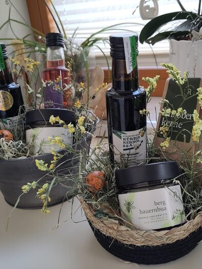 Zwei Körbe mit verschiedenen Flaschen, Kräutern und einem Teelicht. Die Körbe sind mit Trockenblumen und natürlichem Heu dekoriert. | © Imkerei Rosmann
