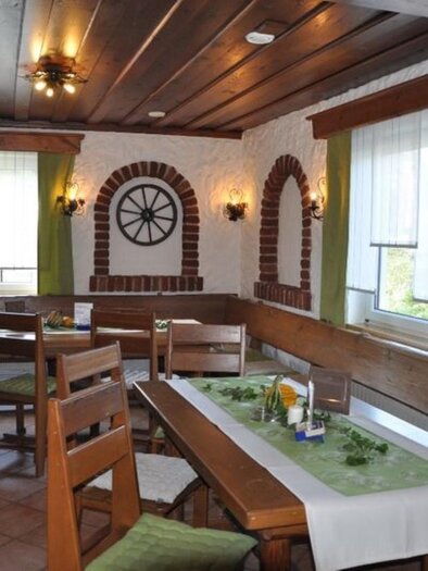 Ein gemütlicher Restaurantraum mit Holzmöbeln und einem rustikalen Ambiente. Große Fenster lassen viel Licht herein und verleihen dem Raum eine einladende Atmosphäre. | © Nostalgiestüberl / Lenz