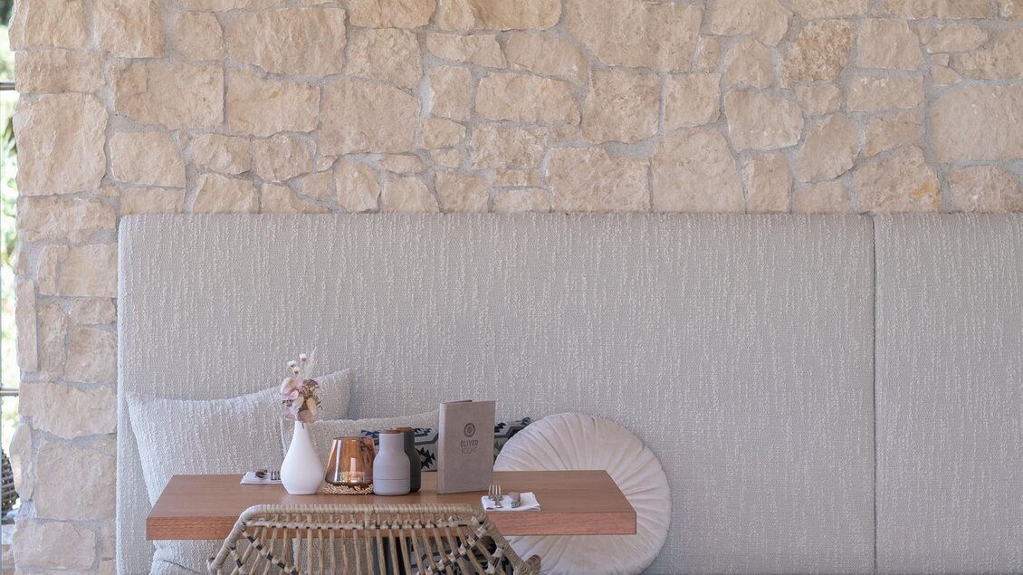 Ein modernes Café mit einer gemütlichen Sitzecke und dekorativen Hängeleuchten. Die Wände sind aus Naturstein und die Einrichtung ist minimalistisch und einladend. | © Oliver kocht