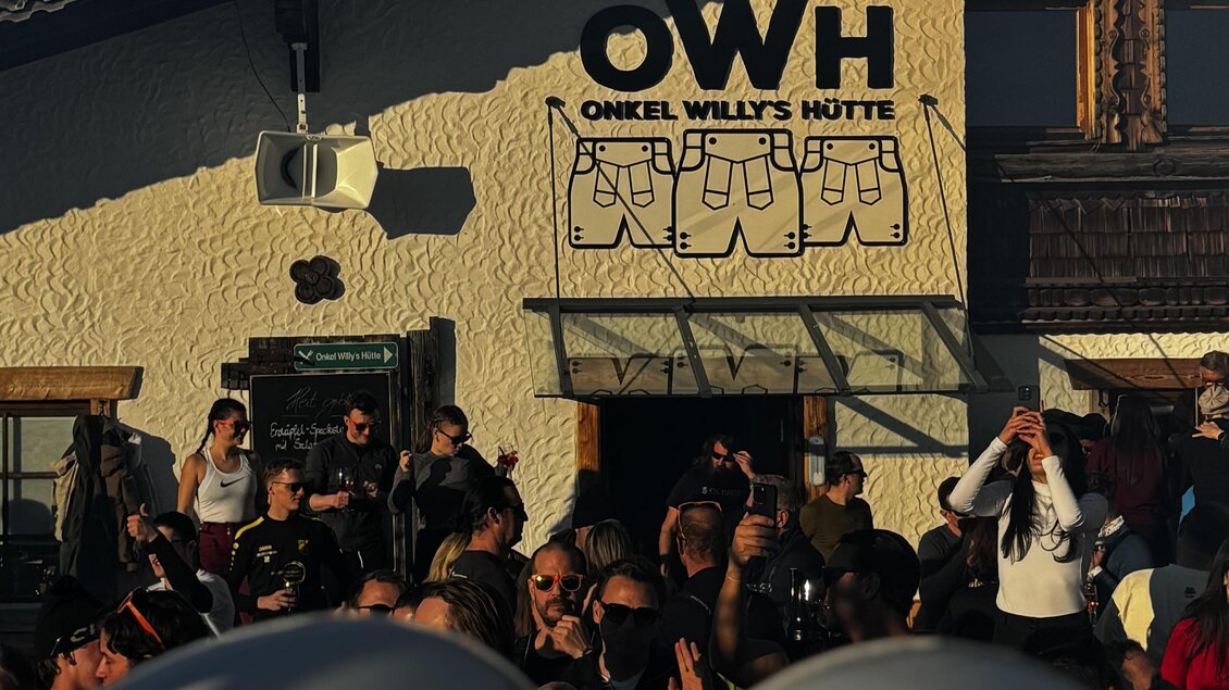 Eine lebhafte Menschenmenge vor einem Hostel mit der Aufschrift "OWH". Die Atmosphäre wirkt festlich und einladend.