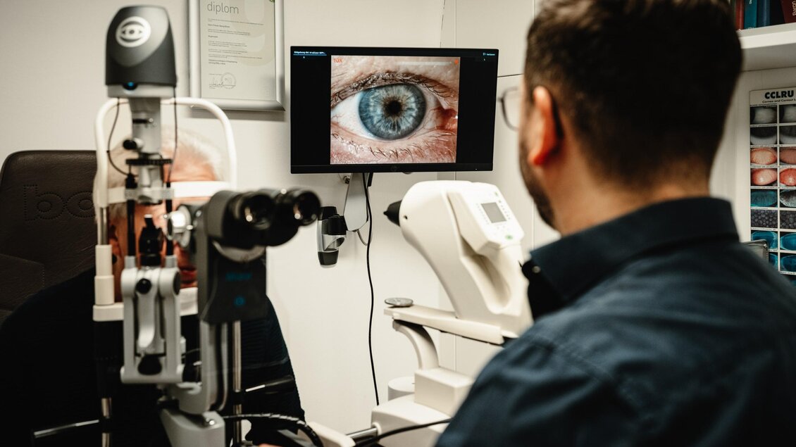 Optiker untersucht das Auge eines Kunden mit einer Spaltlampe bei Optik Rossmann in Graz. | © Bernd Grosseck
