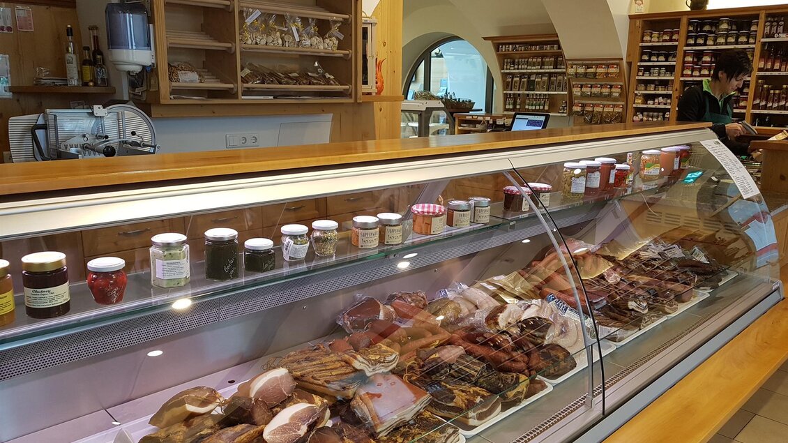 Eine Theke mit einer Auswahl an verschiedenen Wurst- und Schinkenwaren. Im Hintergrund sind Regale mit einmachbaren Lebensmitteln zu sehen. | © Tourismusverband Oststeiermark