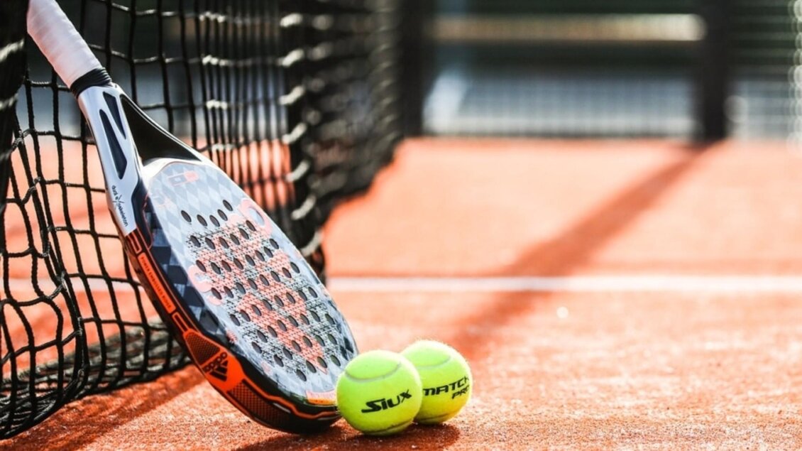 Padel-Schläger und zwei Bälle am Netz auf Sandplatz in der Erlebnisregion Graz. | © Crime Runners