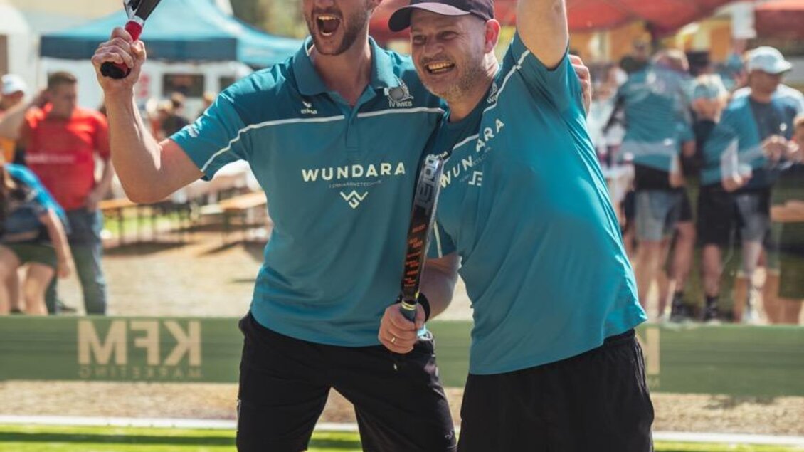 Zwei fröhliche Männer feiern ihren Sieg auf dem Platz. Sie tragen sportliche Kleidung und halten Tennisschläger in der Hand. | © Padelbase Wies