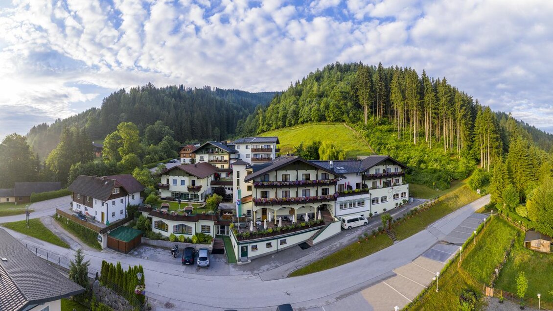 Eine malerische Unterkunft in der Natur mit grünen Hügeln im Hintergrund. Der Himmel ist klar und die Umgebung ist ruhig und einladend. | © Panoramahotel Gürtl 