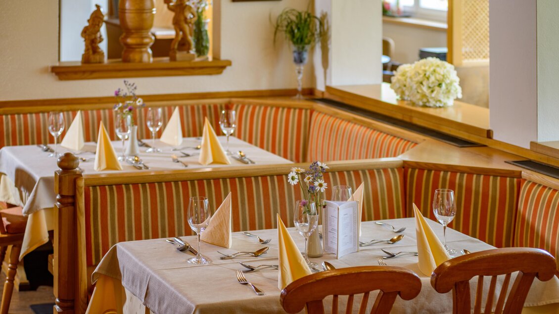 Ein gemütliches Restaurant mit gedeckten Tischen und dekorativen Elementen. Die Tische sind mit weißen Tischdecken und eleganten Bestecken ausgestattet. | © Restaurant