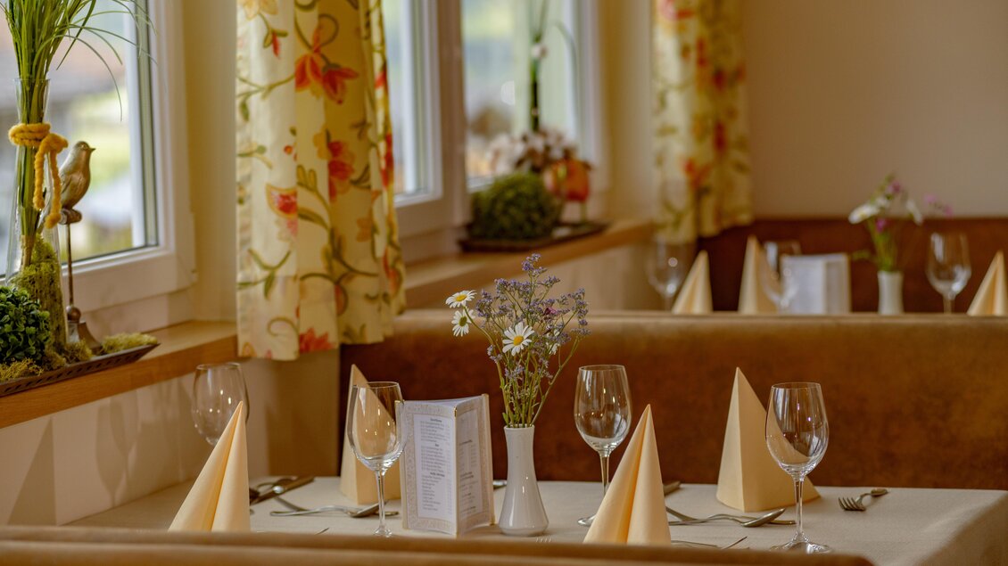 Ein stilvoll gedeckter Tisch in einem Restaurant mit eleganten Stoffservietten und Gläsern. Die Fenster lassen viel Licht hereinfällen und verleihen dem Raum eine gemütliche Atmosphäre. | © Restaurant 