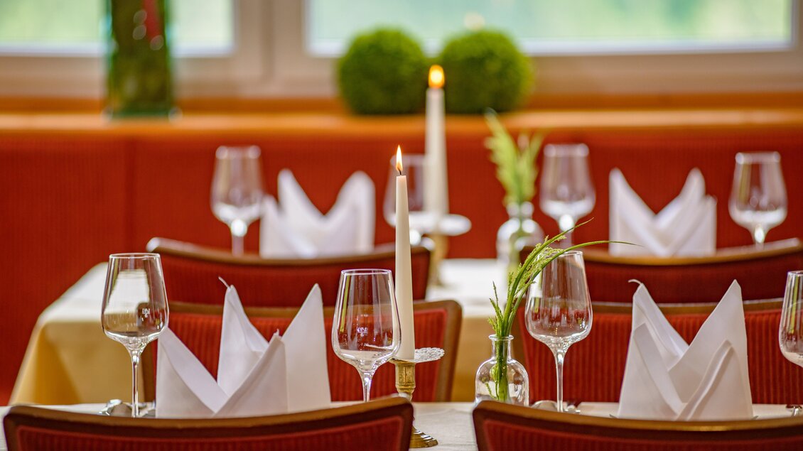 Ein eleganter Restauranttisch mit schön gefalteten Servietten und Gläsern. Eine Kerze sorgt für eine gemütliche Atmosphäre. | © Fichtenstube