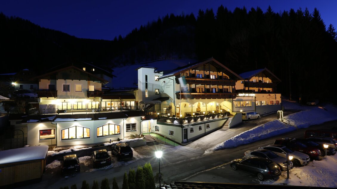 Ein stilvolles Hotel in den Bergen, beleuchtet bei Nacht. Die Umgebung ist schneebedeckt und bietet eine gemütliche Atmosphäre. | © Foto: Raffalt Herbert