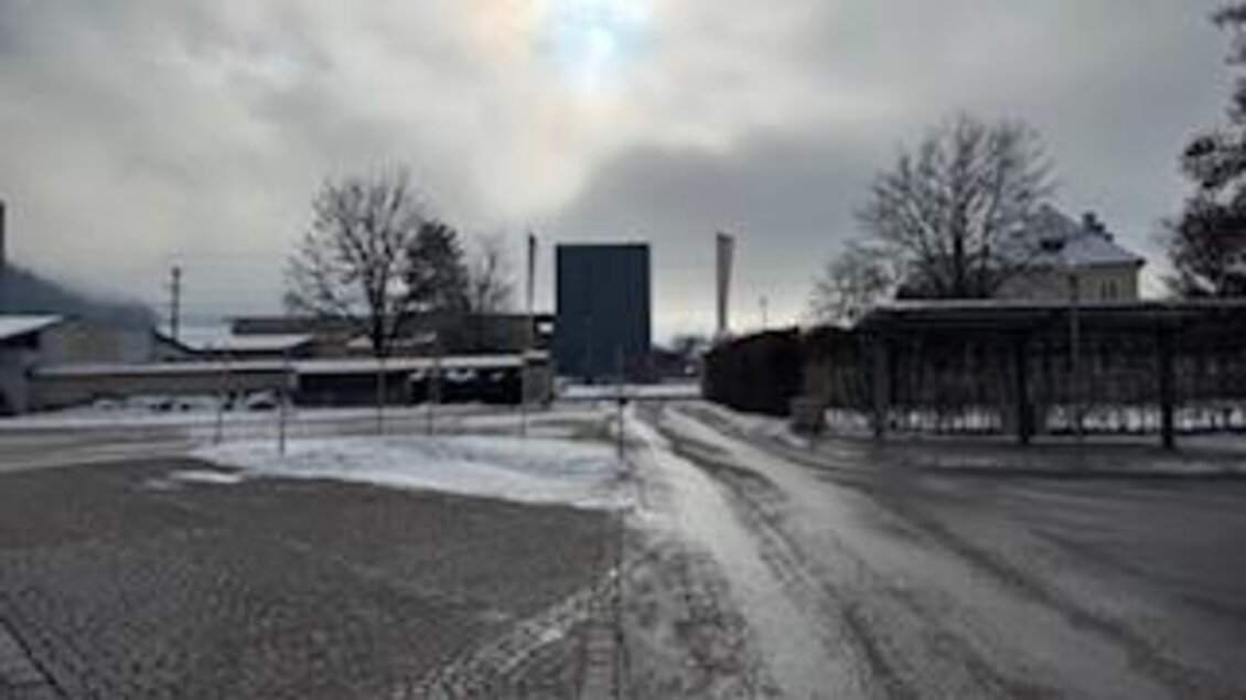 Eine schneebedeckte Straße führt zu einem Industriegebäude. Der Himmel ist bewölkt und es ist eine ruhige Atmosphäre. | © Hanna Giraudo