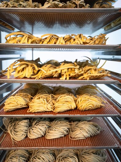 Various types of freshly baked dough goods are lying on several trays in a baking cart. | © Bernd Grosseck