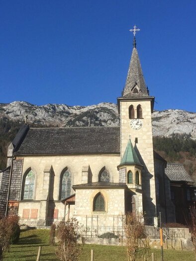 Eine schöne Kirche mit einem hohen Turm, umgeben von Bergen und klarem blauem Himmel. Die Landschaft ist ruhig und malerisch. | © Bettina Scheck