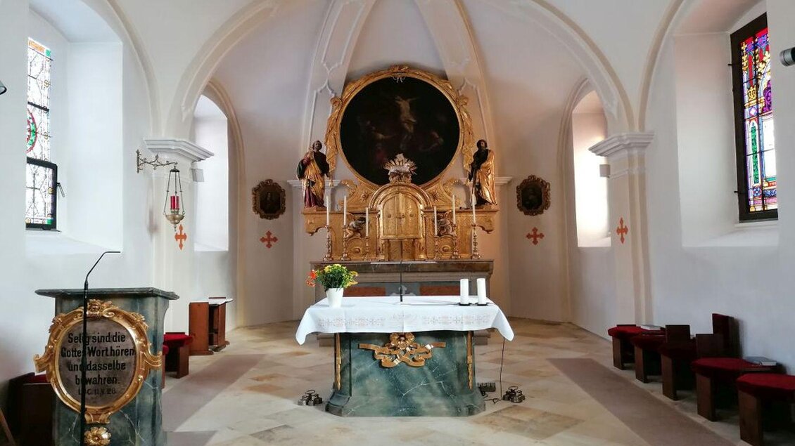 Der elegante Kirchenraum von der Pfarrkiche in Tauplitz mit einem Altar aus Holz und marmornem Tisch. Farbige Fenster strahlen Licht in den Raum und schaffen eine ruhige Atmosphäre. | © TVB Ausseerland Salzkammergut/Kolb