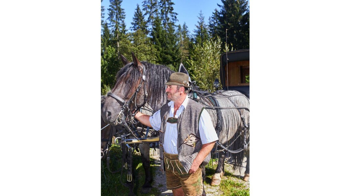 <p>Kutschenfahrer Rudolf Seebacher steht zufrieden neben seinem vor die Kutsche eingespannten Pferd, mit dem er eine ruhige und vertraute Verbundenheit ausstrahlt.</p> | © Elisabeth Seebacher
