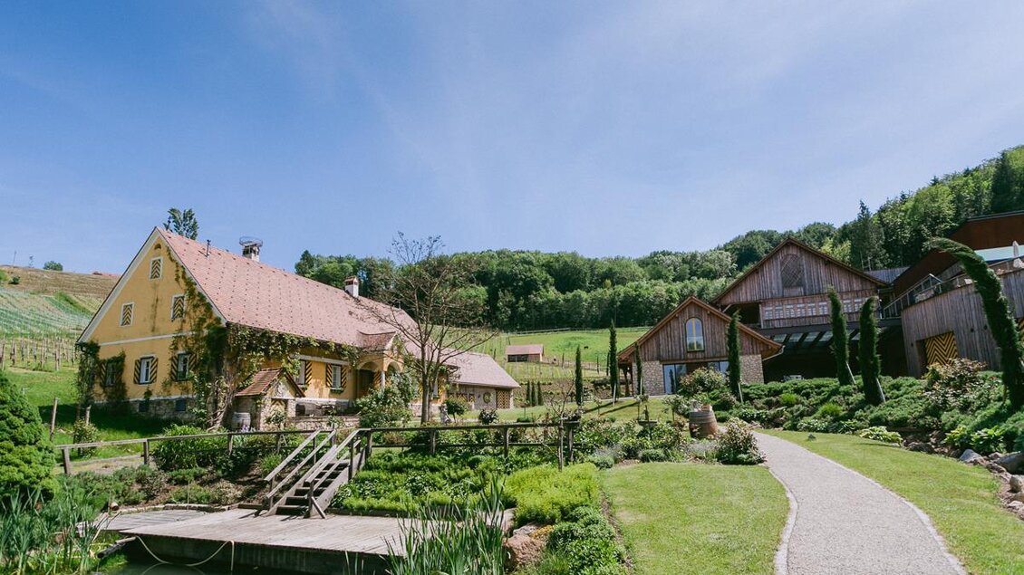 Ein malerisches Bauernhaus mit einem großen Garten und einem kleinen Teich. Umgeben von sanften Hügeln und einer grünen Landschaft. | © Weingut Georgiberg