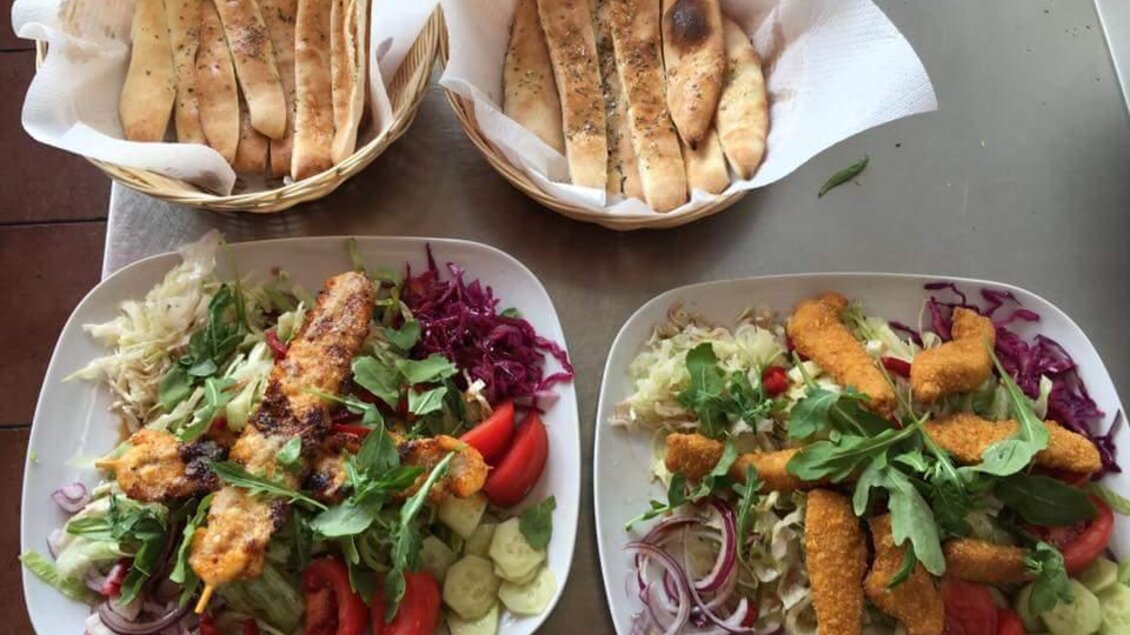 Zwei Teller mit buntem Salat, frittierten Snacks und frischen Gemüse liegen auf einem Tisch. Im Hintergrund sind Körbe mit knusprigem Brot zu sehen. | © Pizzeria Passail