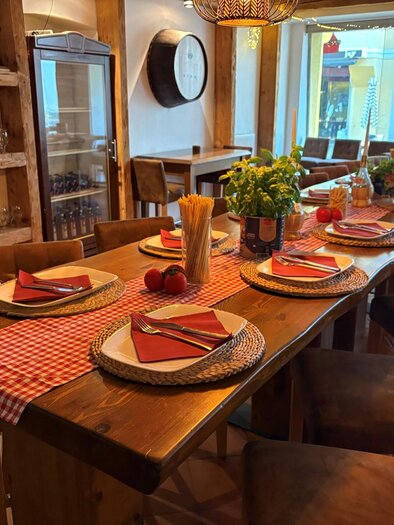 A stylishly set table in a restaurant with wooden chairs. Colorful napkins, plates, and fresh flowers are on the table. | © San Marco