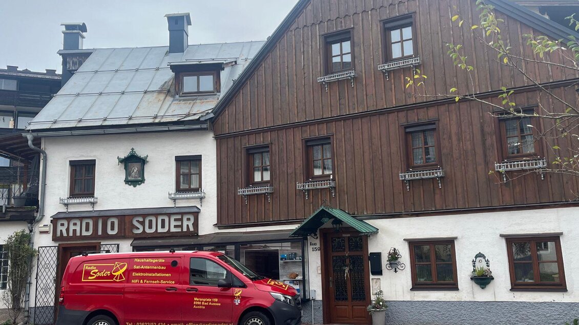 Ein traditionelles Gebäude mit Holzfassade und einem grauen Dach. Vor dem Gebäude steht ein roter Lieferwagen mit dem Aufdruck „Radio Soder“. | © TVB Ausseerland Salzkammergut_ Nathalie Schröttenhamer